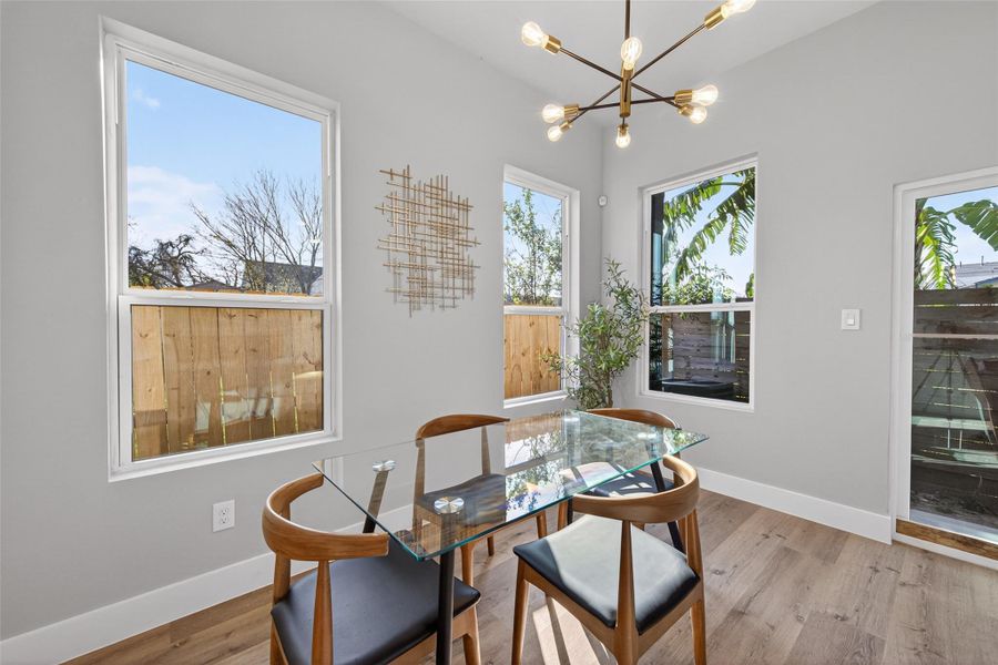 Dining area framed by large windows, statement modern chandelier, and clean architectural lines—perfect for intimate dinners or hosting guests in style.
