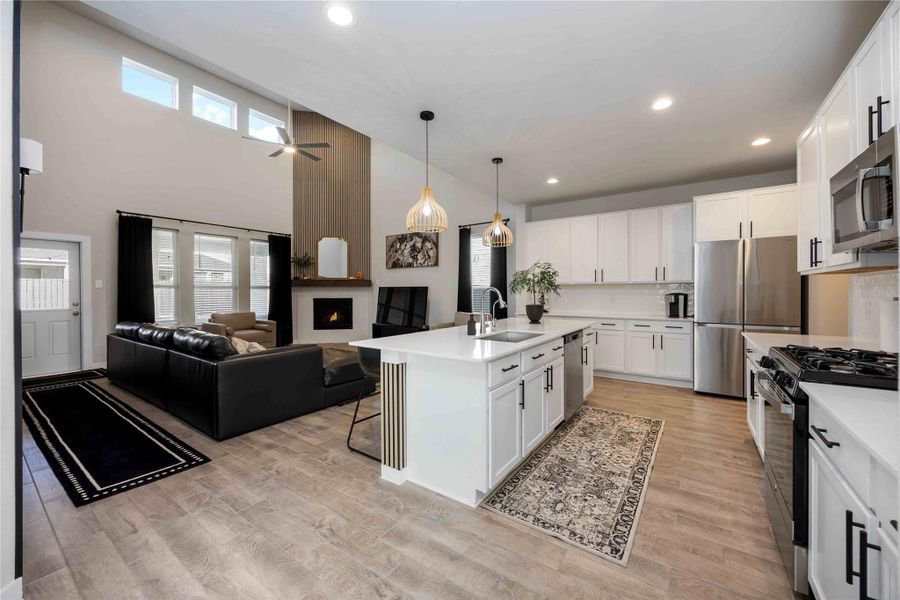 Open living room with high ceilings, fireplace, and large windows. Open living room with high ceilings, fireplace, and large windows.