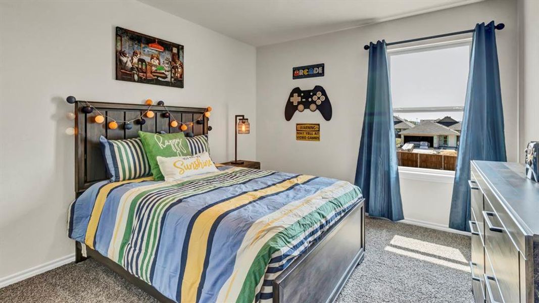Carpeted room featuring a window with roller shades and blue drapes, a dark wood headboard, and light gray walls Carpeted room featuring a window with roller shades and blue drapes, a dark wood headboard, and light gray walls