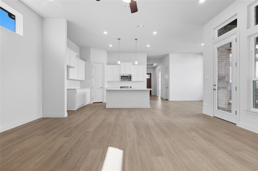 Unfurnished living room featuring light wood-style flooring, a ceiling fan, and recessed lighting