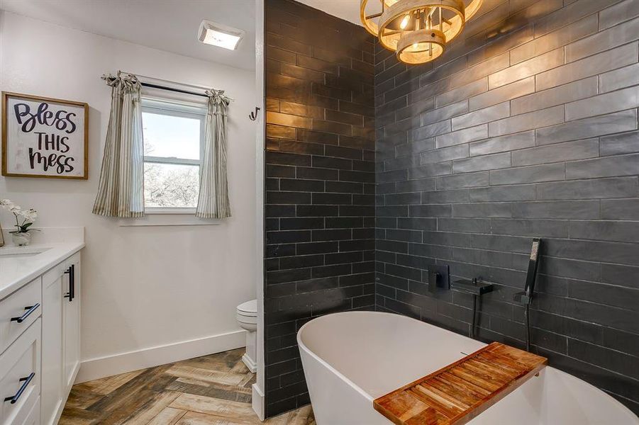 Full bath with vanity, parquet flooring, and a freestanding bath