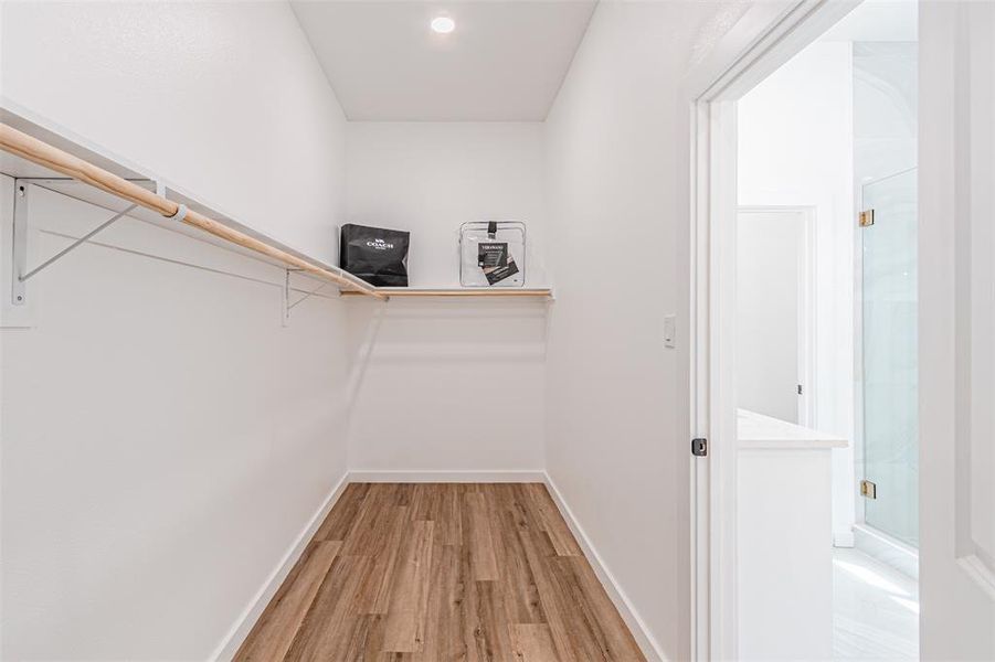 Walk in closet with light wood finished floors