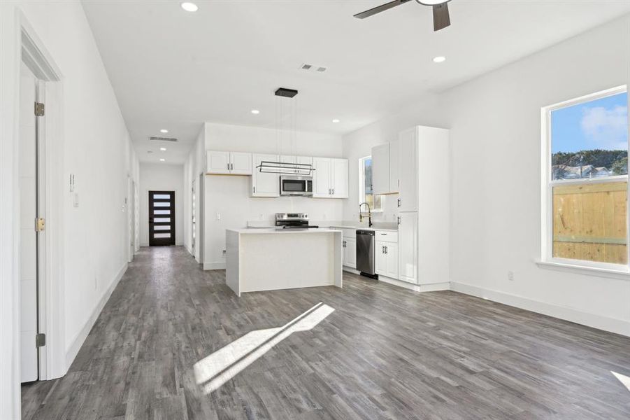 Kitchen with stainless steel appliances, white cabinets, a kitchen island, and wood finished floors