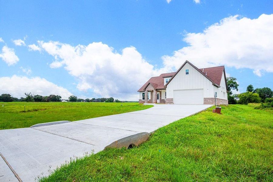 Charming countryside home with a spacious driveway, set against open fields and a bright blue sky, offering serene rural living. Charming countryside home with a spacious driveway, set against open fields and a bright blue sky, offering serene rural living.