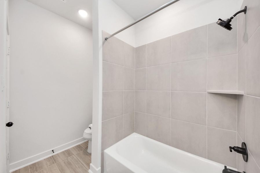 Jack-and-Jill secondary bath offers a sleek tile surround, modern black fixtures, and a separated toilet and shower area for improved privacy and flow.