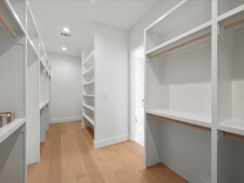 Walk in closet with light wood-style flooring
