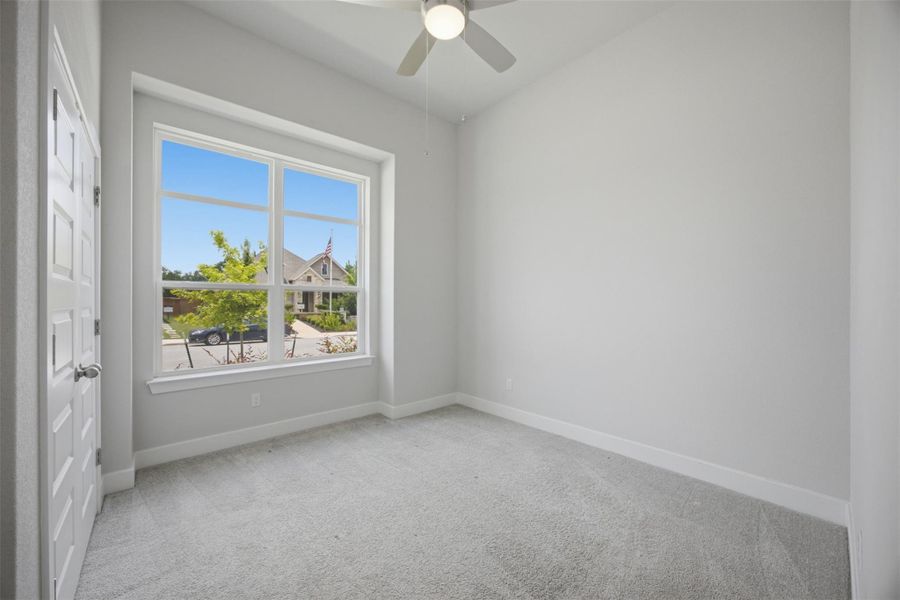 A well-lit bedroom offers carpeted floors and a window with a view of the neighborhood.