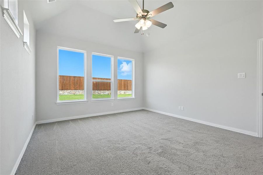 Spare room featuring carpet floors, a ceiling fan, and vaulted ceiling