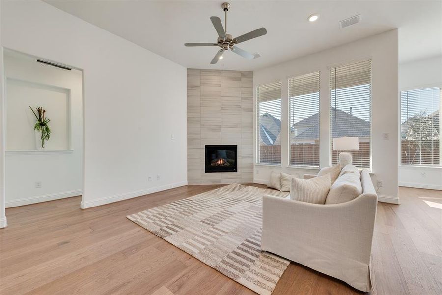 Living room with a fireplace, light wood-type flooring, and ceiling fan