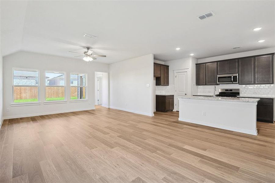 Kitchen with backsplash, stainless steel appliances, ceiling fan, and light hardwood / wood-style floors