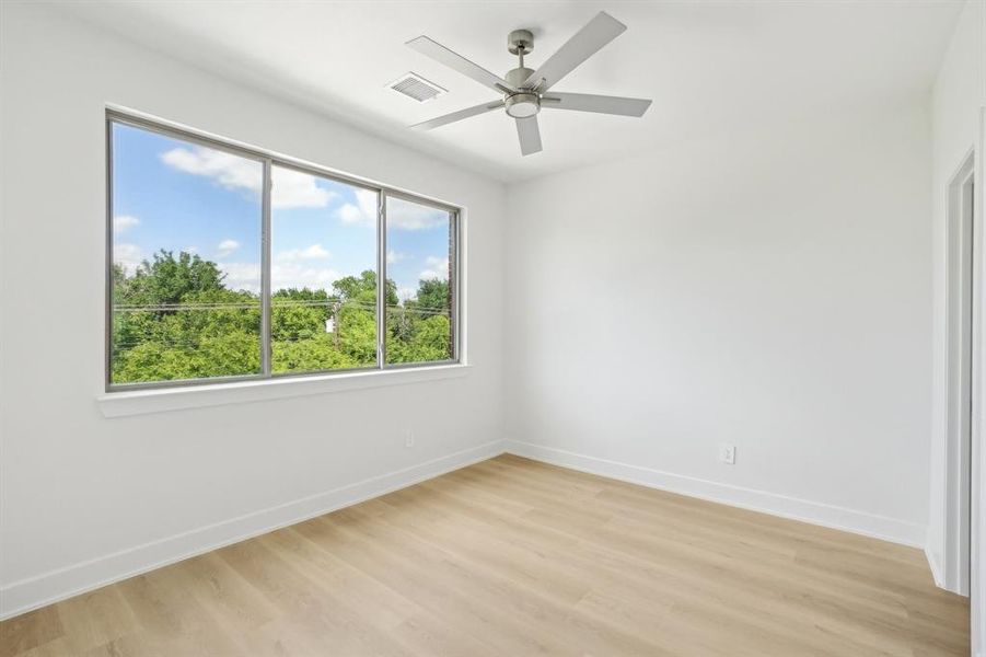 Empty room featuring baseboards, light wood-type flooring, and a ceiling fan
