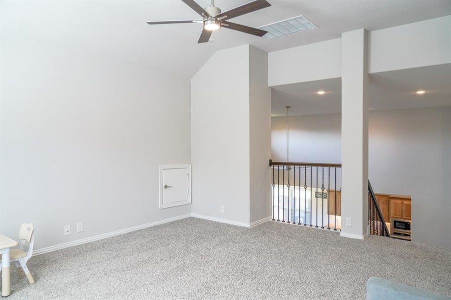 Carpeted spare room featuring ceiling fan and lofted ceiling