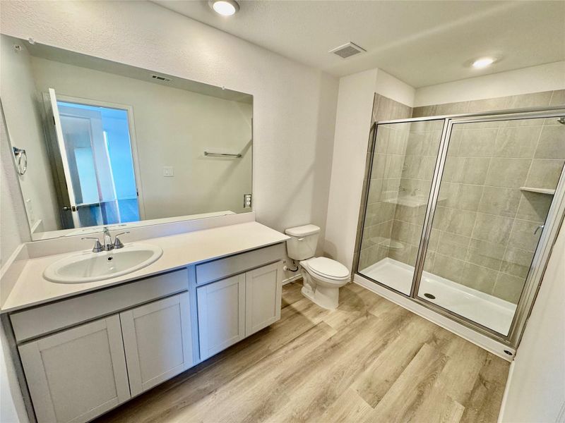 Full bathroom featuring vanity, a stall shower, light wood-style flooring, and recessed lighting