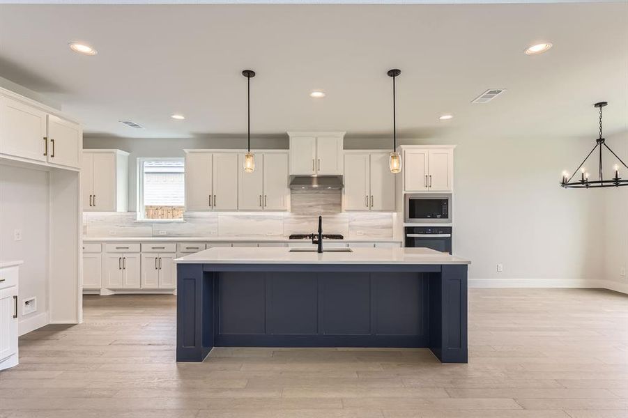 Kitchen with stainless steel microwave, under cabinet range hood, oven, white cabinetry, and recessed lighting