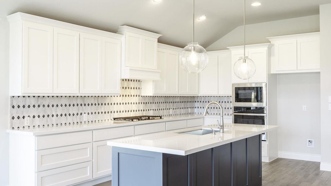 Kitchen with light wood finished floors, a sink, stainless steel appliances, decorative backsplash, and light countertops Kitchen with light wood finished floors, a sink, stainless steel appliances, decorative backsplash, and light countertops