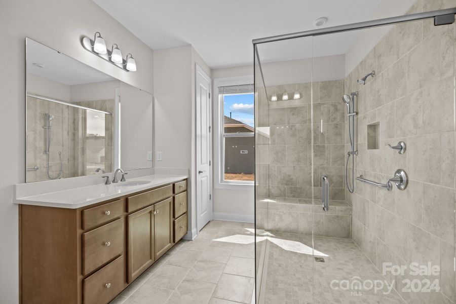 Large, fully tiled "spa-like" walk-in shower with seat has added grab bar and handheld shower.