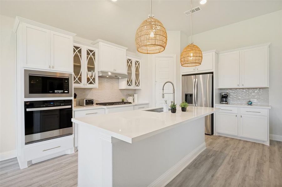At the center of the home, this stunning chef's kitchen showcases a sprawling quartz island, double ovens, stainless steel appliances, and abundant storage. Thoughtfully designed for entertaining, the open layout blends style and functionality while creating a natural gathering space for family and friends At the center of the home, this stunning chef's kitchen showcases a sprawling quartz island, double ovens, stainless steel appliances, and abundant storage. Thoughtfully designed for entertaining, the open layout blends style and functionality while creating a natural gathering space for family and friends