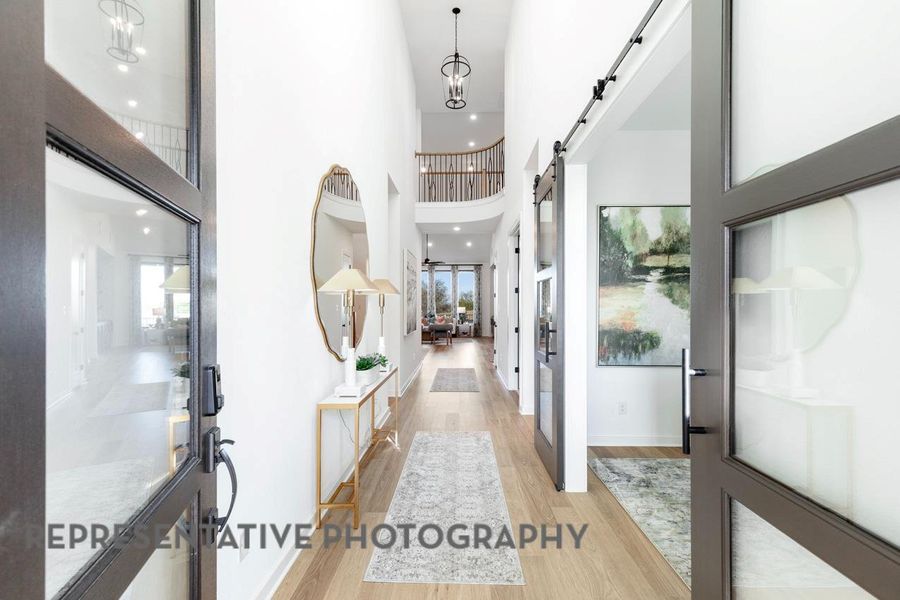 Entryway with a barn door, light wood-style flooring, and a high ceiling
