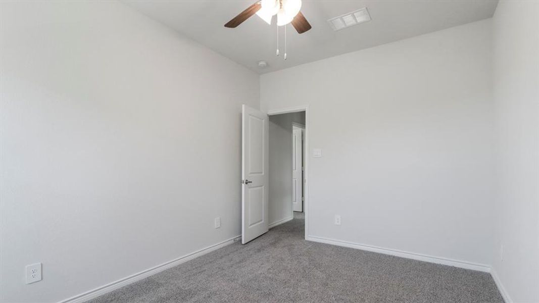 Carpeted empty room with baseboards and a ceiling fan