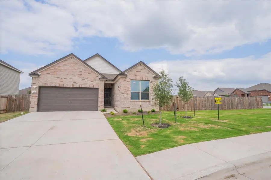Brick facade residence with an attached garage, concrete driveway, and front lawn Brick facade residence with an attached garage, concrete driveway, and front lawn