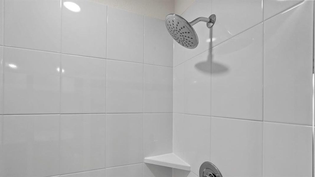 Shower enclosure with white square tiles, a rainfall shower head, and a built-in corner shelf