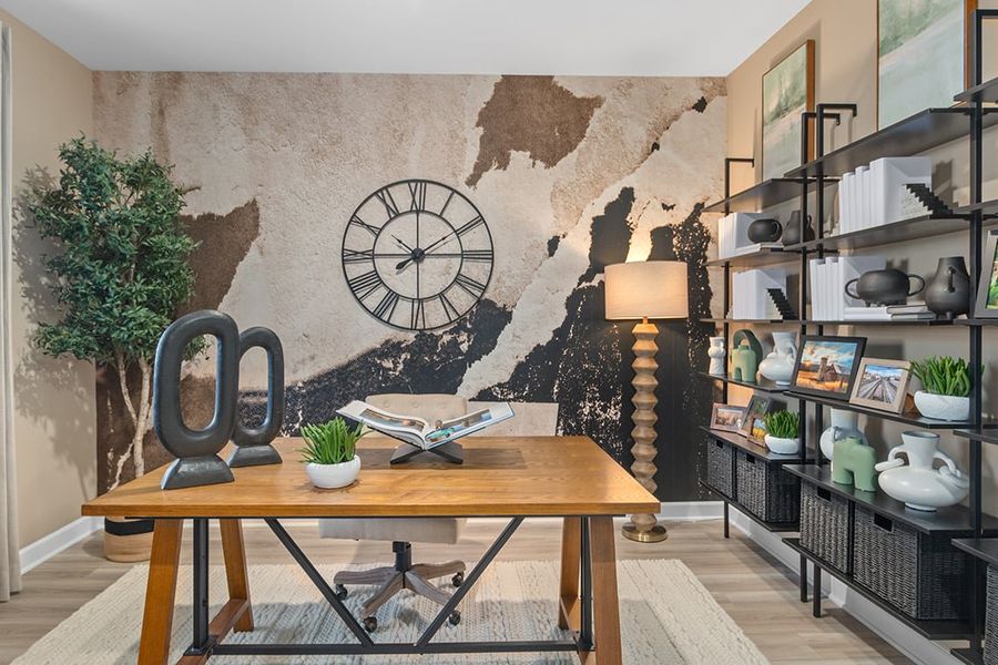 A table with a lamp and books on it in a room with shelves. A table with a lamp and books on it in a room with shelves.