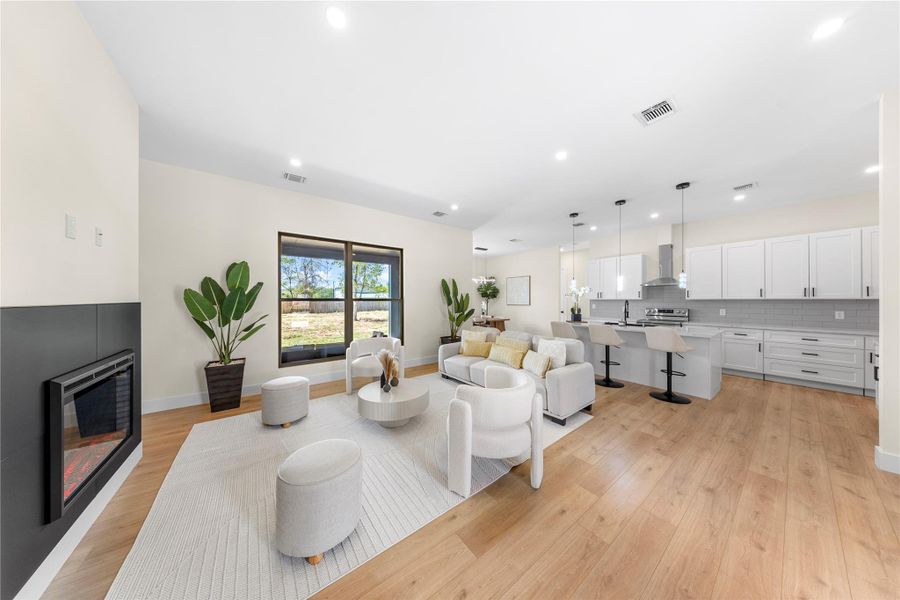 Living area with a glass covered fireplace, recessed lighting, and light wood-style flooring Living area with a glass covered fireplace, recessed lighting, and light wood-style flooring