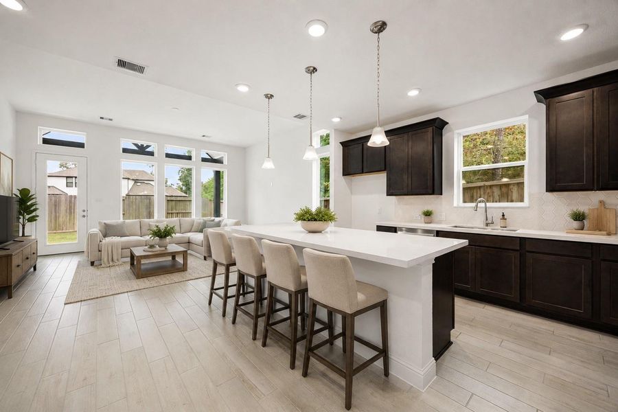 Experience modern elegance in this virtually staged open-concept living space, featuring a sleek kitchen with dark wood cabinetry and a spacious island, seamlessly flowing into a bright living area with abundant natural light. ***Virtually Staged***