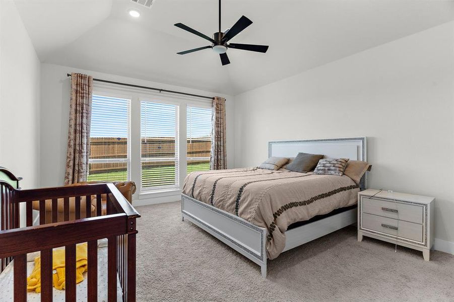 Bedroom with lofted ceiling, carpet flooring, a ceiling fan, and baseboards Bedroom with lofted ceiling, carpet flooring, a ceiling fan, and baseboards