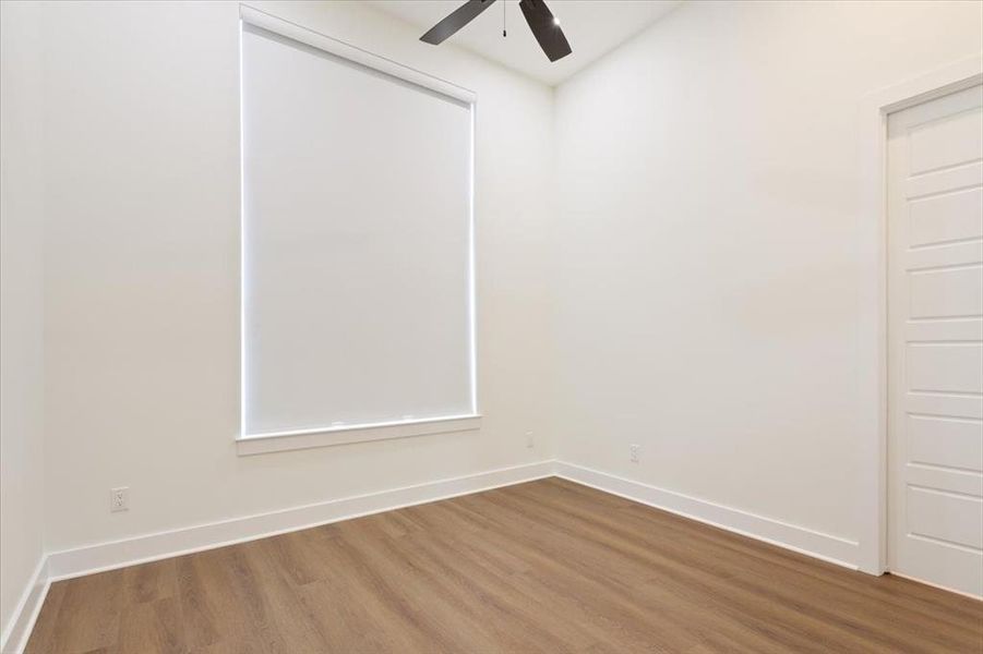Empty room with wood finished floors and a ceiling fan