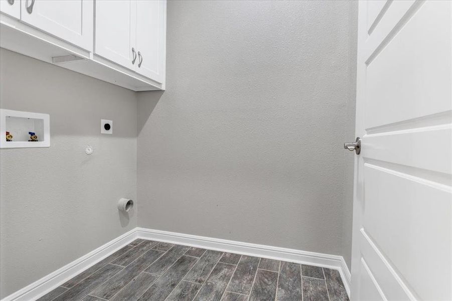 Washroom featuring wood finish floors, cabinet space, hookup for an electric dryer, gas dryer hookup, and washer hookup