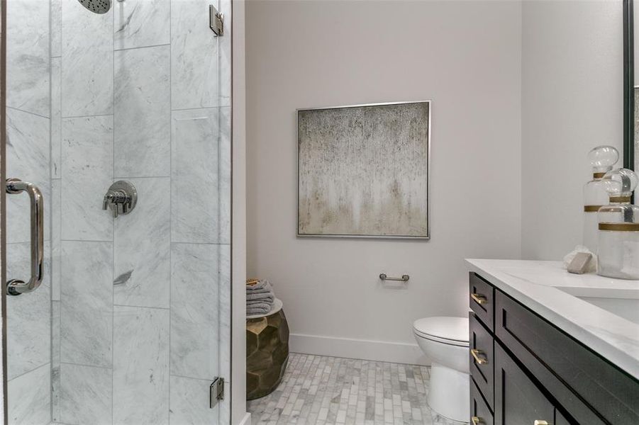 Bathroom with tile flooring, an enclosed shower, vanity, and toilet