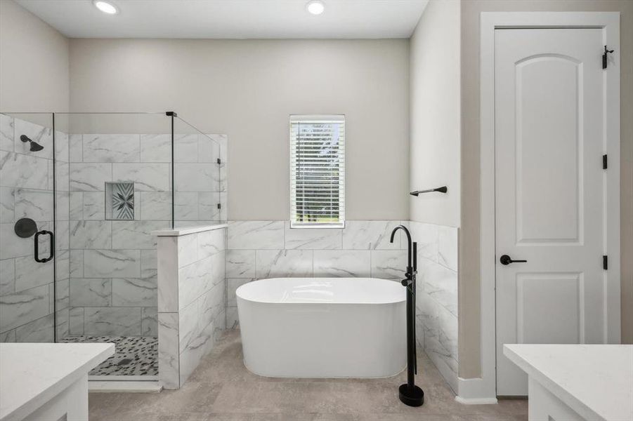 Bathroom featuring tile walls, shower with separate bathtub, vanity, and tile patterned flooring