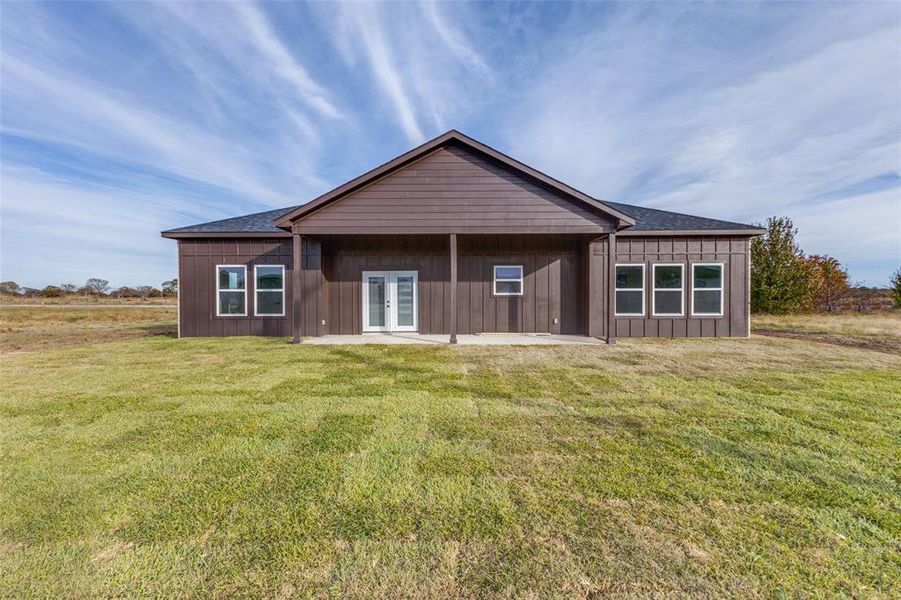 Rear view of property featuring a lawn, french doors, and a patio