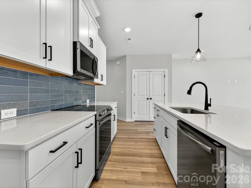 42" White cabinets, Quartz countertops, tiled backsplash. Large kitchen island with shiplap accent, Frigidaire Appliances. Cooking is exhaust vented to the outside