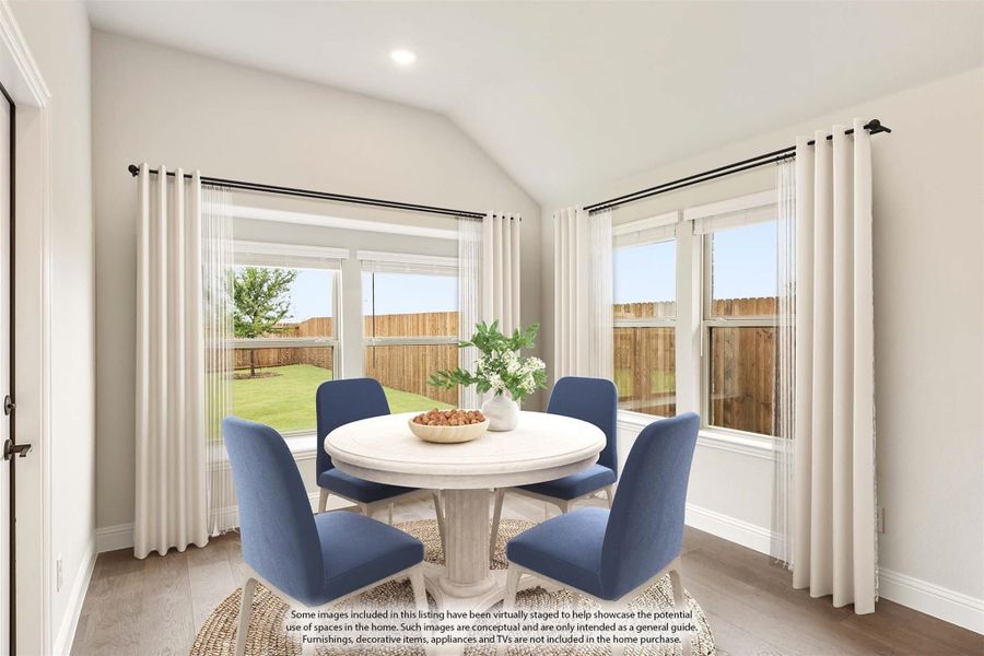 Breakfast nook with round white table, four blue chairs, vaulted ceiling, and large windows overlooking backyard Breakfast nook with round white table, four blue chairs, vaulted ceiling, and large windows overlooking backyard