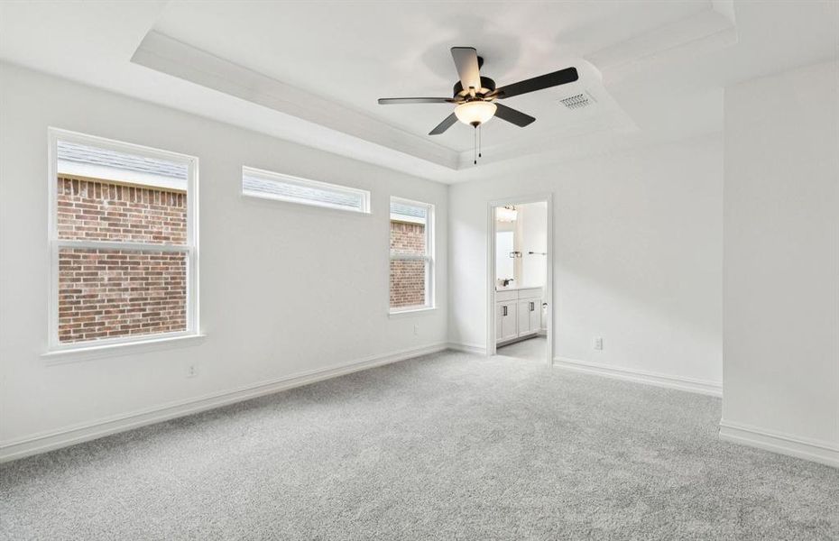 Expansive owner's suite with impressive windows and elegant tray ceiling  *Real home pictured