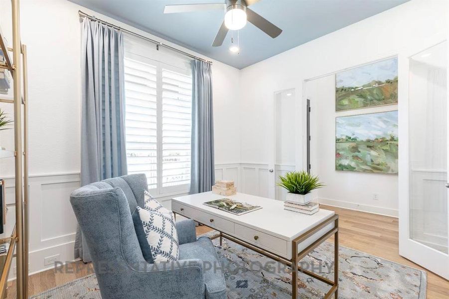 Office area featuring light wood finished floors, healthy amount of natural light, wainscoting, and a ceiling fan Office area featuring light wood finished floors, healthy amount of natural light, wainscoting, and a ceiling fan