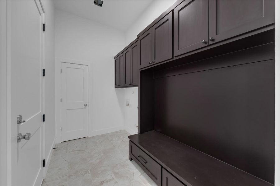Laundry/Mud Room; Rich dark cabinetry and tiled flooring define this practical mudroom entry space.