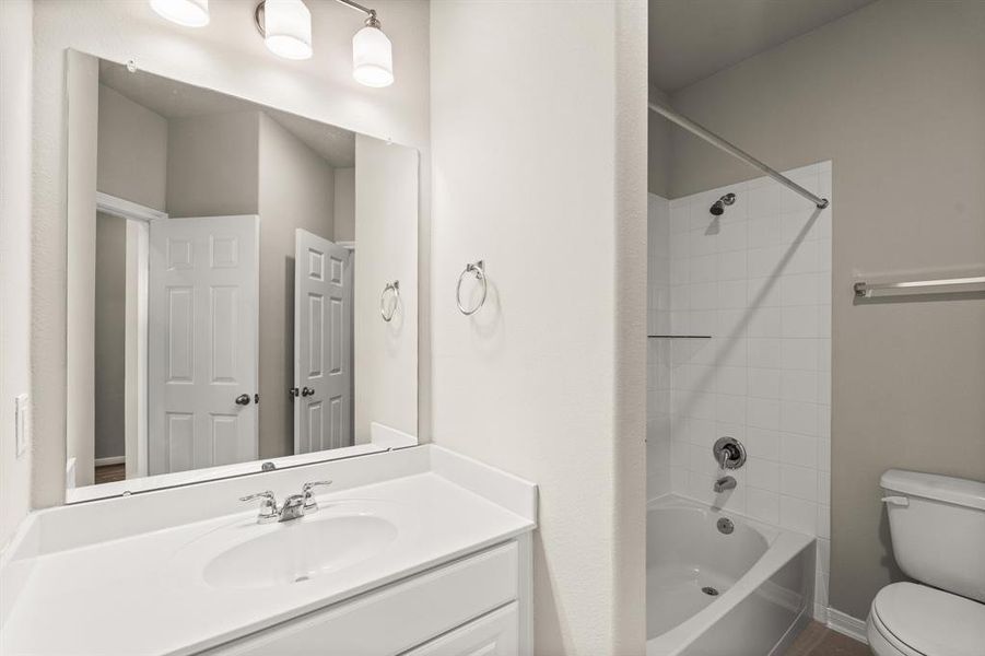 The secondary bath features tile flooring, white cabinetry and light countertops and a shower/tub combo. Perfect for accommodating any visiting family and friends.