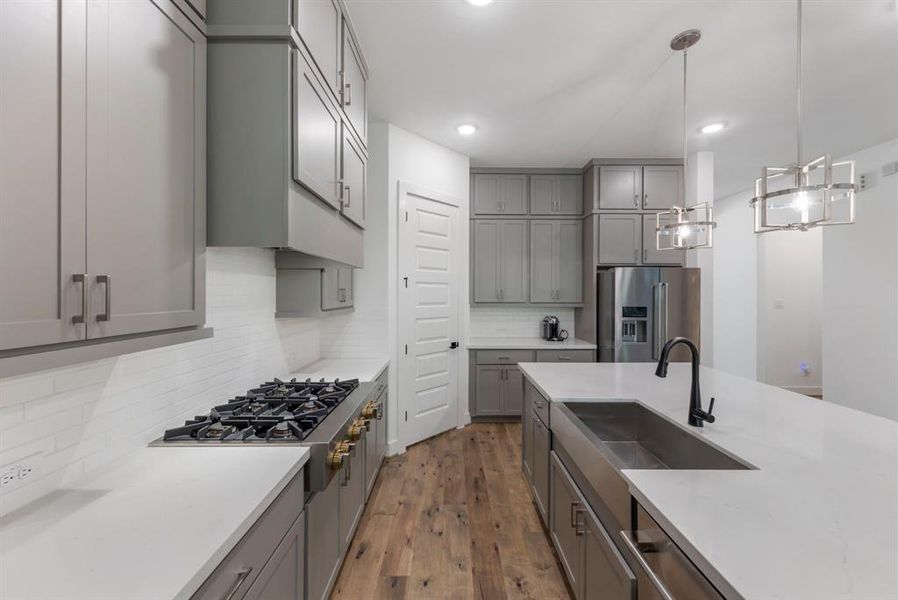 The kitchen boasts sleek countertops, a stylish tile backsplash, a spacious sink, and a gas cooktop, all designed to elevate your cooking experience.