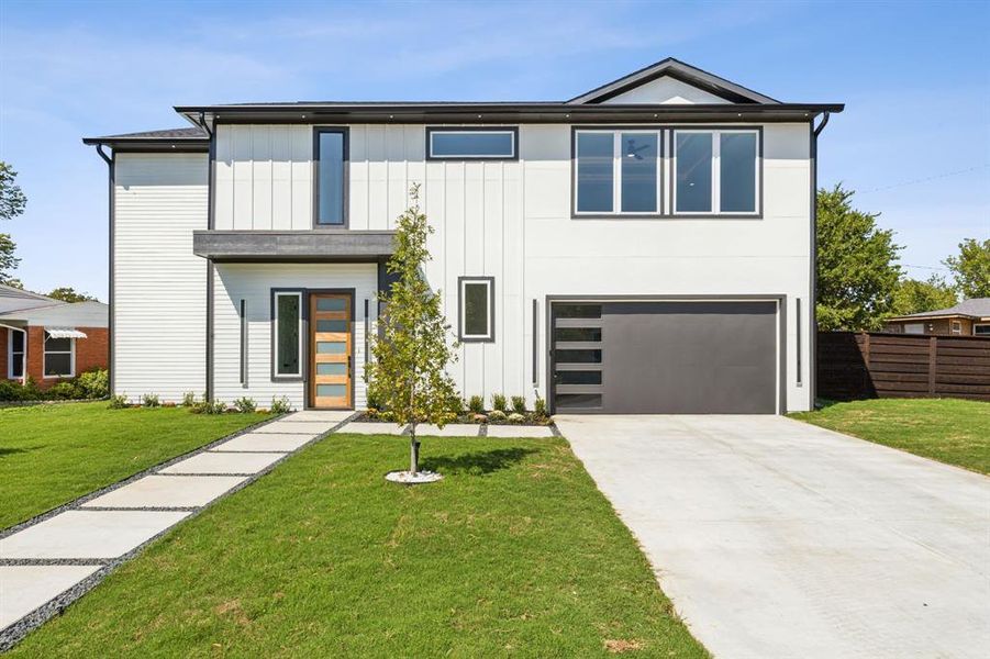 View of front of home with a garage and a front lawn