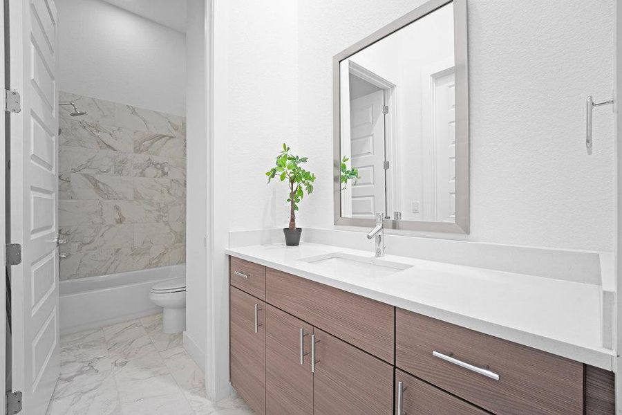 Bathroom featuring vanity, bathing tub / shower combination, and light marble finish floors