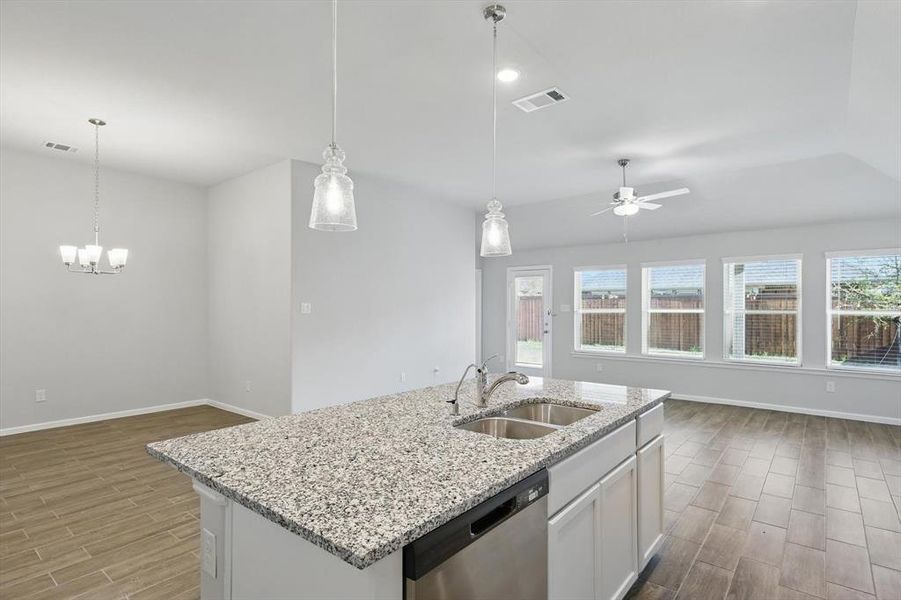 Kitchen featuring stainless steel dishwasher, wood tiled floors, open floor plan, and ceiling fan Kitchen featuring stainless steel dishwasher, wood tiled floors, open floor plan, and ceiling fan