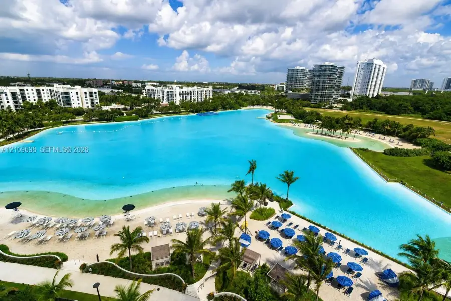Expansive man-made lagoon featuring sandy beaches, mature palm trees, and manicured landscaping
