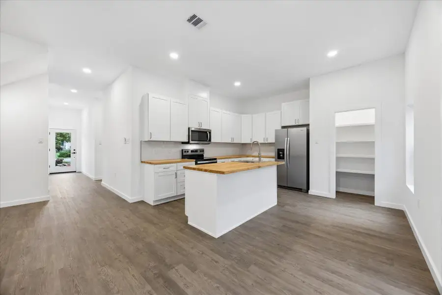 A streamlined kitchen design with light wood countertops and modern stainless-steel appliances awaits culinary adventures.