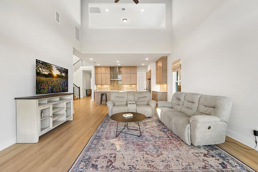 Soaring ceilings and warm wood floors anchor this expansive open-concept main level.