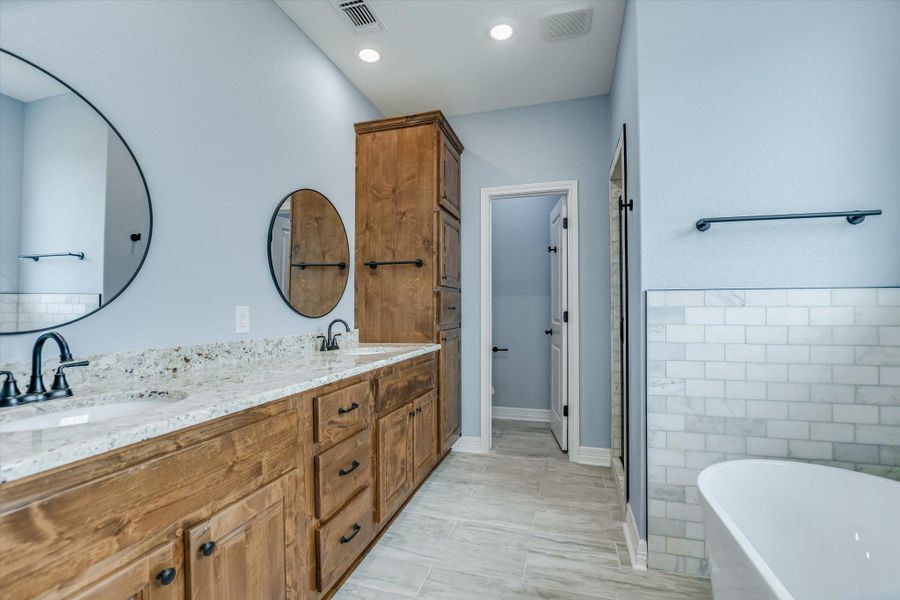 Bathroom with a soaking tub, double vanity, a stall shower, and tile walls