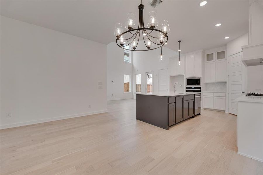 Kitchen with white cabinets, open floor plan, pendant lighting, light wood finished floors, and recessed lighting Kitchen with white cabinets, open floor plan, pendant lighting, light wood finished floors, and recessed lighting