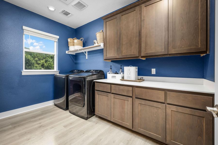 Ample cabinetry and expansive counter space create an organized and efficient laundry haven.